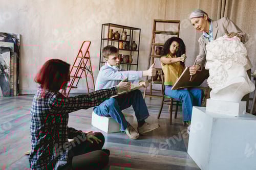 Preview: Mature teacher talking with her students during class in art school