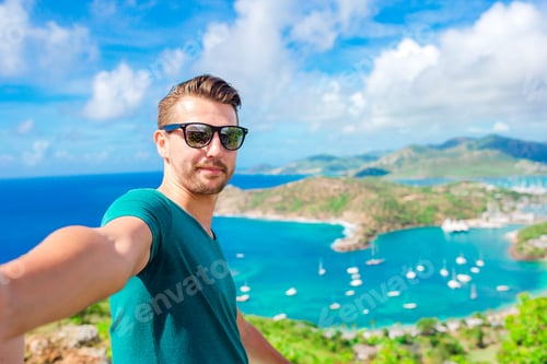 Preview: Young man taking selfie with view of English Harbor from Shirley Heights, Antigua