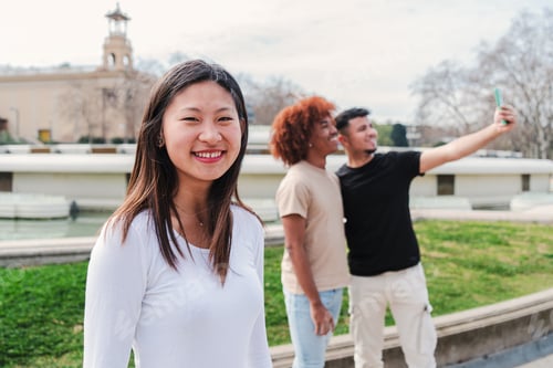 Preview: On foreground one joyful asian school girl student looking smiling at camera while her friends take
