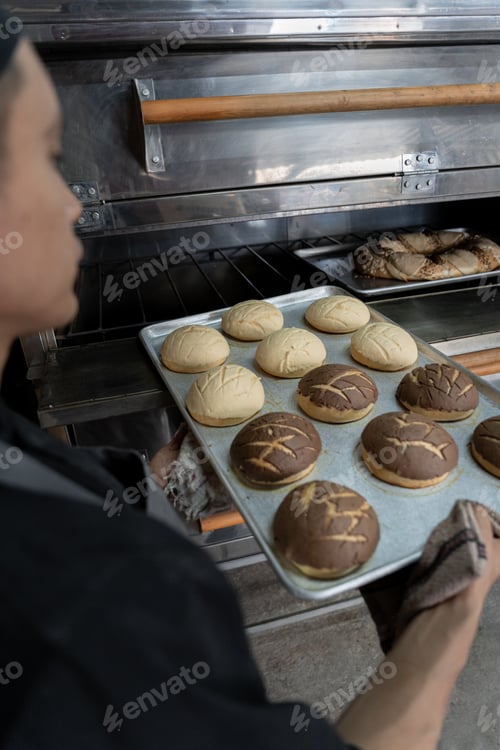 Preview: A young Hispanic baker pulling Mexican shells out of the oven