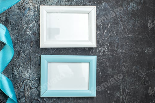 Preview: Top view of blue and white picture frames blue ribbon on icy black background