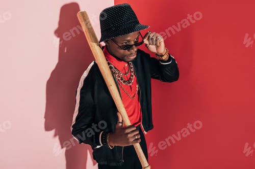 Preview: high angle view of stylish african american man with baseball bat adjusting sunglasses and looking