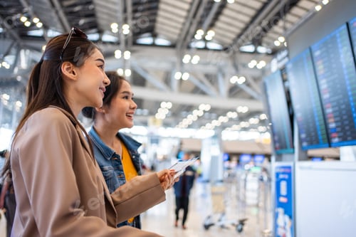 Preview: Asian young women passenger checking depature boarding pass in airport.