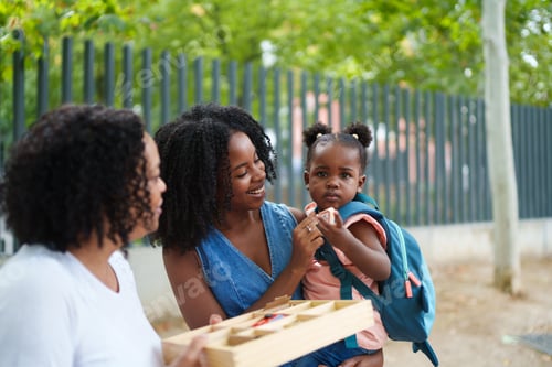 Preview: Mother and grandmother giving educational toy to little girl in park