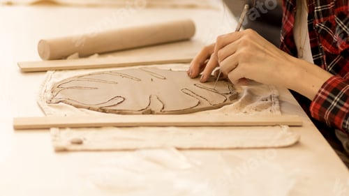 Preview: female hands carve a plate from clay
