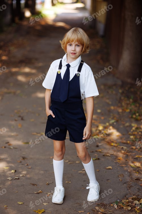 Preview: Young schoolgirl in school uniform standing on the sidewalk. Back to school.