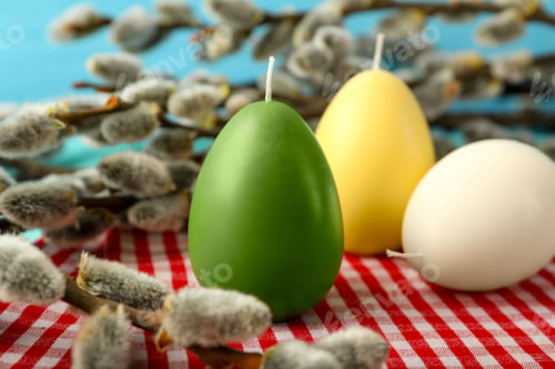 Preview: Colorful egg-shaped candles and willow branches on table, closeup. Easter decor