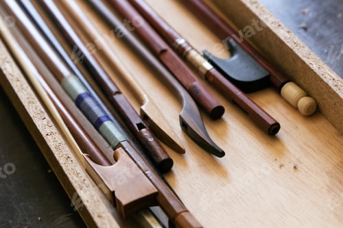 Preview: Pile of violin bows collected in a wooden box in the luthier's workshop for repair