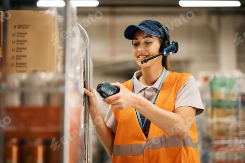 Preview: Happy female worker using bar code reader while scanning packages in a warehouse.