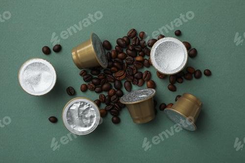 Preview: Coffee capsules and coffee beans on green background, top view