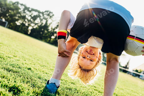 Preview: Boy on soccer field, bending over, looking through his legs