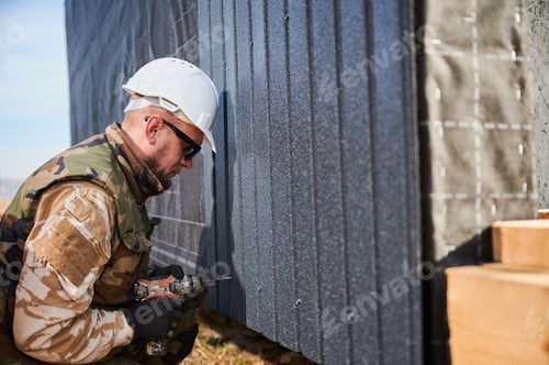 Preview: Builder installing corrugated iron sheet used as facade of future wooden frame house.