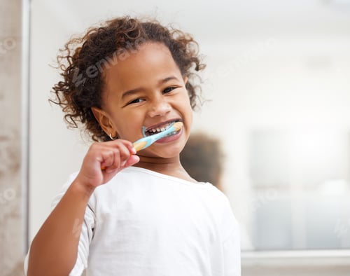 Preview: Portrait of an adorable little girl brushing her teeth in a bathroom at home