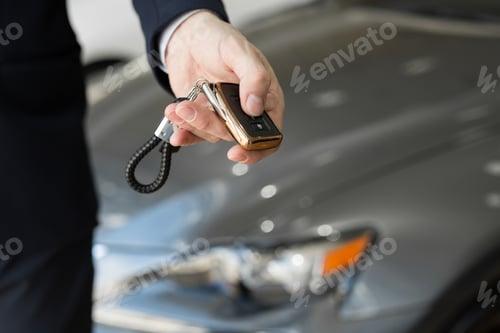 Preview: A car dealer with a key in a car dealership close-up