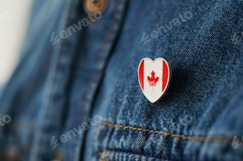 Preview: Canadian flag icon is pinned on blue jeans jacket. Canada patriotism concept.