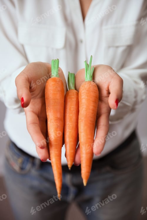 Preview: Young woman hands with carrot