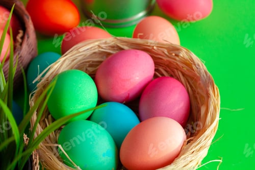 Preview: Vibrant colored eggs in a nest on green. Easter concept