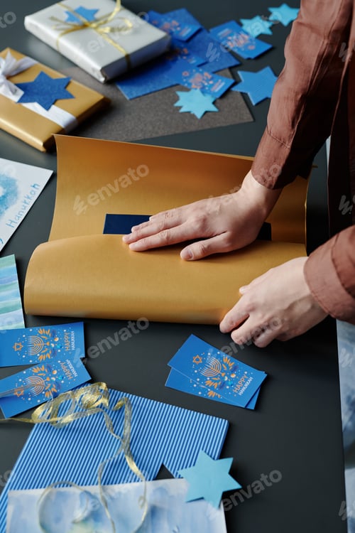 Preview: Hands of young woman wrapping book or some other item into beige paper