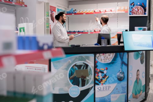 Preview: Pharmacy workers looking at drugs packages while working at pills inventory