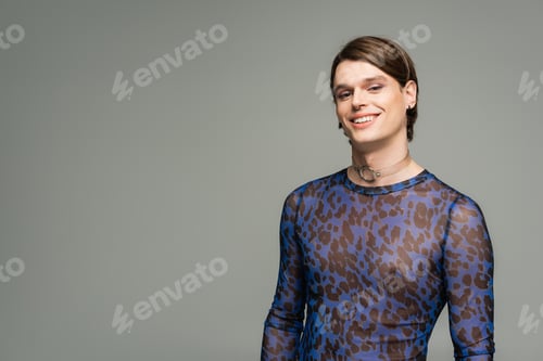 Preview: carefree pangender person in blue animal print top smiling at camera isolated on grey