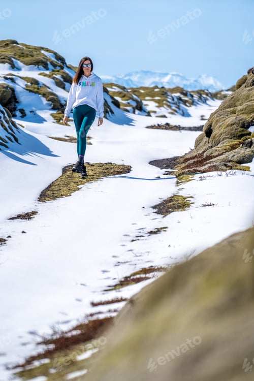 Preview: Woman walking on a snowy road on a sunny day in Iceland