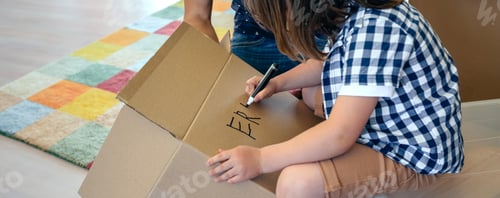 Preview: Child Writing on Cardboard Box Moving Into New Home