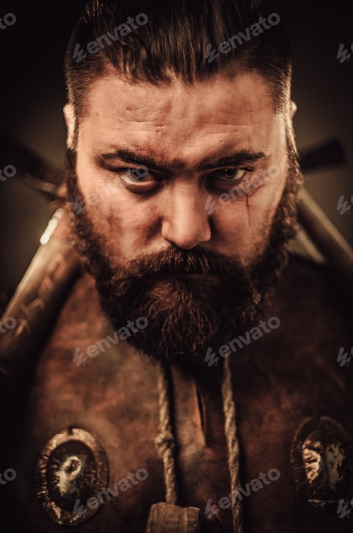 Preview: Angry viking with ax in a traditional warrior clothes, posing on a dark background.