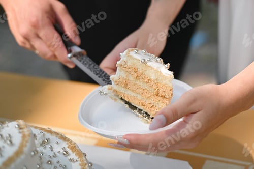 Preview: Woman holds plate as man serves slice of cake in casual moment.