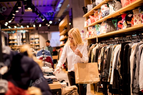 Preview: Young woman with shopping bags standing at the clothing store