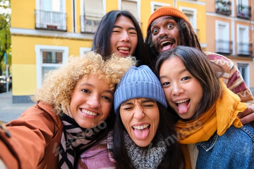 Preview: Multiracial group of friends having fun and taking a selfie outdoors on street.
