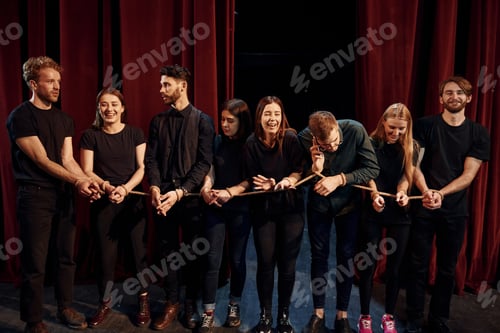 Preview: With rope in hands. Group of actors in dark colored clothes on rehearsal in the theater