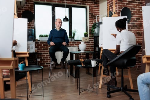 Preview: Man teacher explaining art technique to diverse team during art course