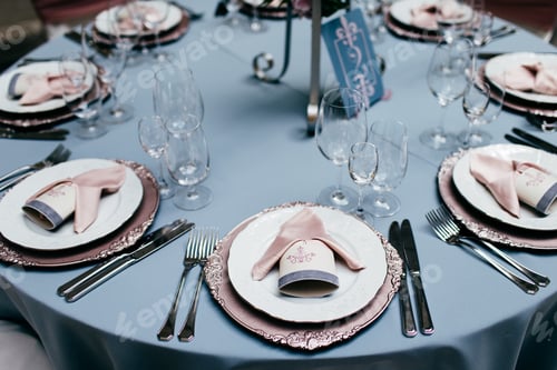 Preview: Table setting with empty plates, forks, glasses and knives and light blue tableclothes.