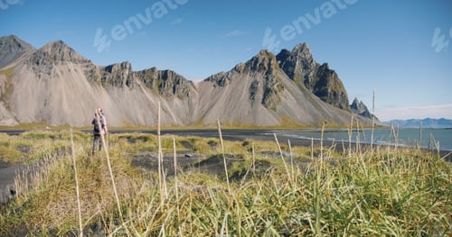 Preview: Morning scene of female traveler exploring Stokksnes cape with Vestrahorn in background Sunny summer