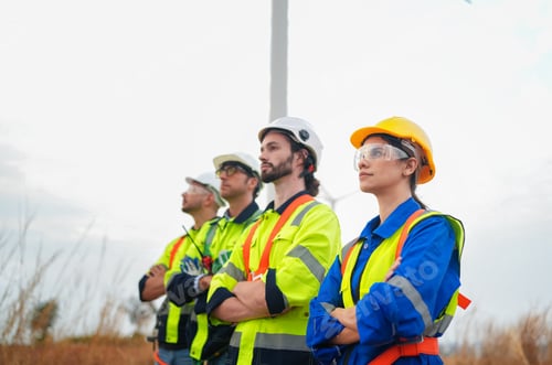 Preview: Wide perspective of wind turbine engineers walking with coworker in wind farms