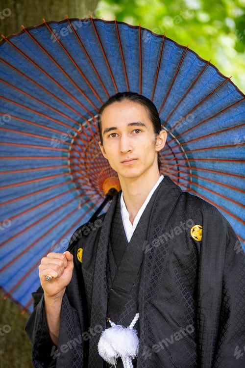 Preview: A serene portrait of a man dressed in traditional Japanese attire, holding a vibrant blue umbrella.