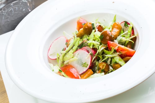 Preview: Fresh summer salad with vibrant vegetables served in a white bowl on a dining table