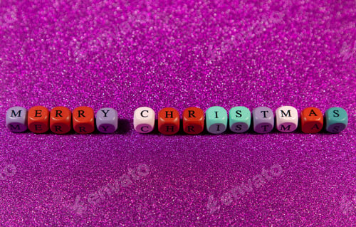 Preview: Set of multi-colored wooden cubic beads spelling out 'Merry Christmas' on a purple background