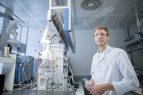 Preview: Portrait of young male scientist holding sample bottle in lab