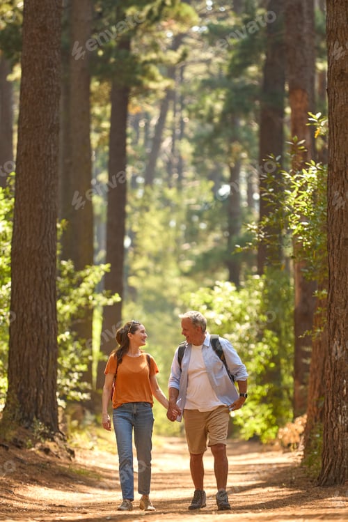 Preview: Senior Retired Couple Holding Hands Hiking Along Trail In Countryside
