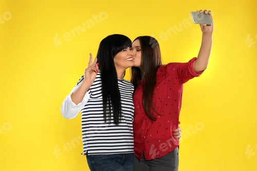 Preview: Young woman and her mother taking selfie on color background