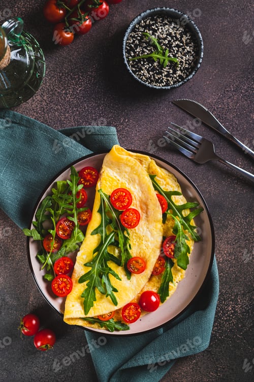 Preview: Omelette pancake with cherry tomatoes and arugula on a plate on the table top and vertical view