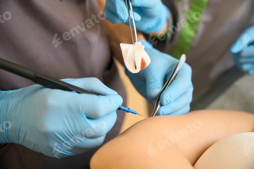 Preview: Dermatologic surgeon and a medical assistant performing dermal lesion removal