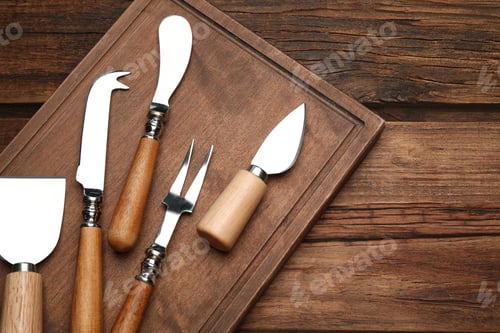 Preview: Cheese knives and fork on wooden table, flat lay
