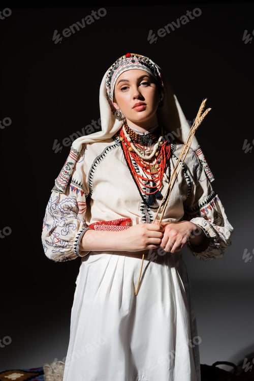 Preview: young ukrainian woman in traditional clothing with ornament holding wheat spikelets on black