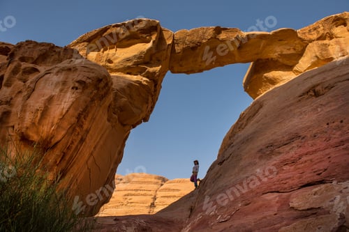 Preview: Tourist posing under the Um Fruth rock bridge in Wadi Rum desert, Jordan