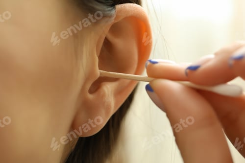 Preview: Woman cleans her ears with a cotton swab, close up