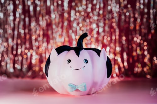 Preview: Funny and cute pink Vampire pumpkin with blue butterfly tie and golden tinsel curtain