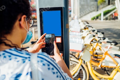 Preview: Young woman unlocking bike rent using smartphone - Woman paying wireless for renting bike sharing