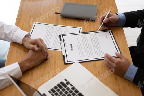 Preview: The manager holding the papers is reading the resume and interviewing the applicant in the office.